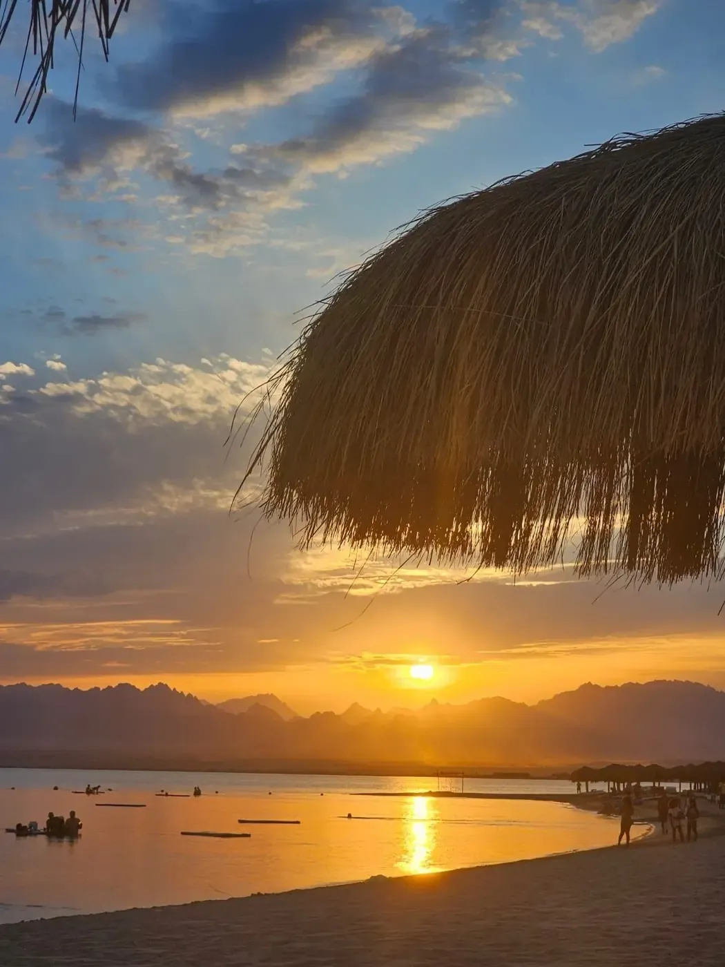 Golden sunset over a sheltered Somabay beach beneath a thatched umbrella